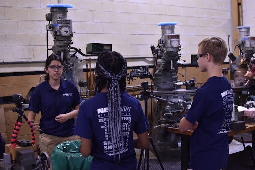 New Way Air Bearings’ intern from Drexel University, Lauren Lugones, demonstrates to two E.T.Richardson Middle School students how one piece of manufacturing equipment at New Way works to create Porous Media Air Bearings.