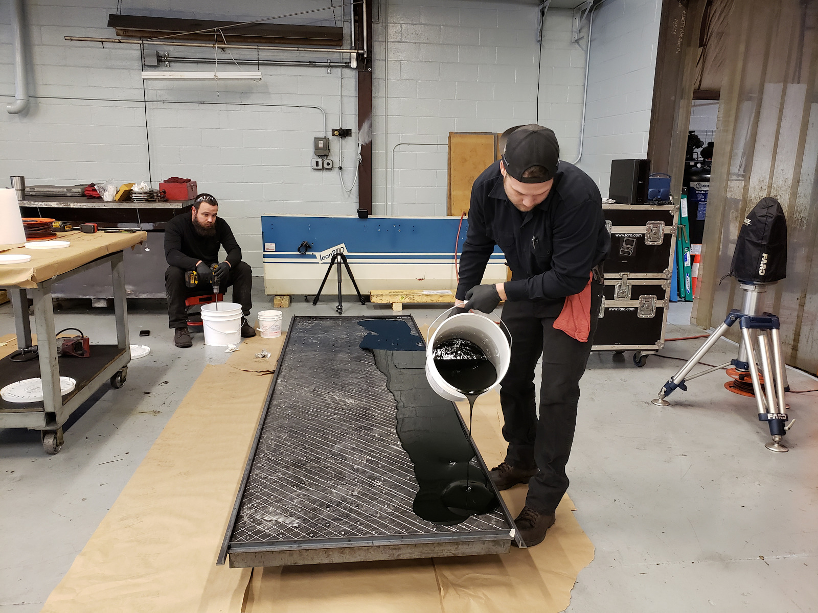 Technician pouring epoxy over steel plate.
