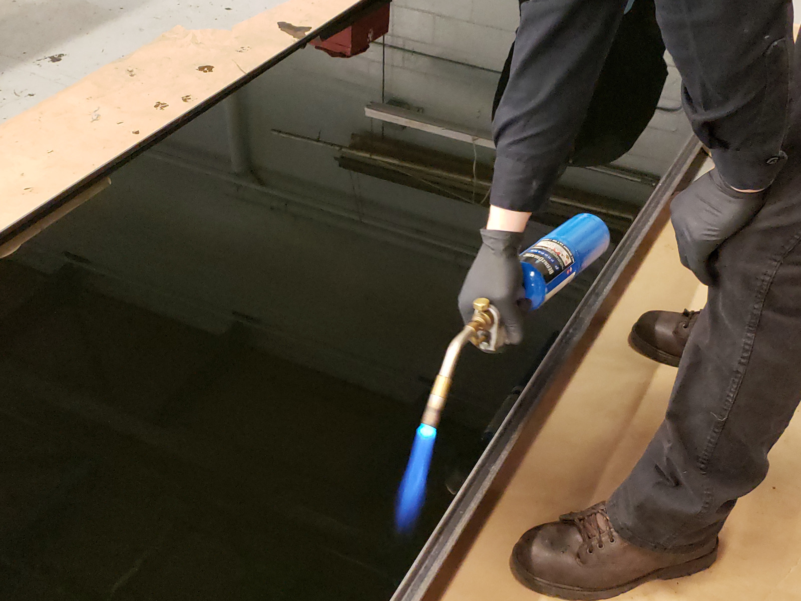 Technician utilizing torch to pop bubbles on epoxy surface.