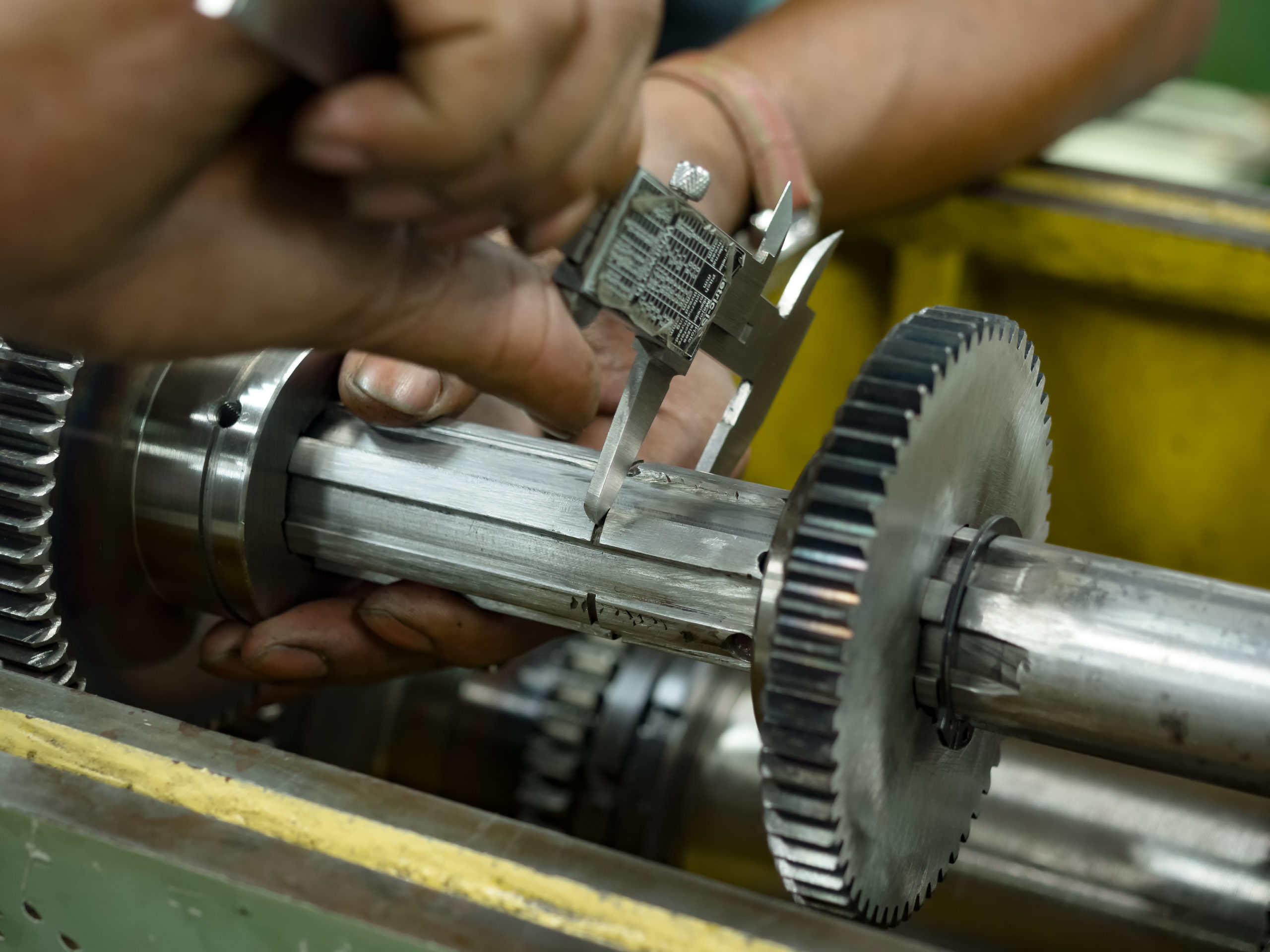 Individual measures the diameter of a shaft with a pair of calipers.