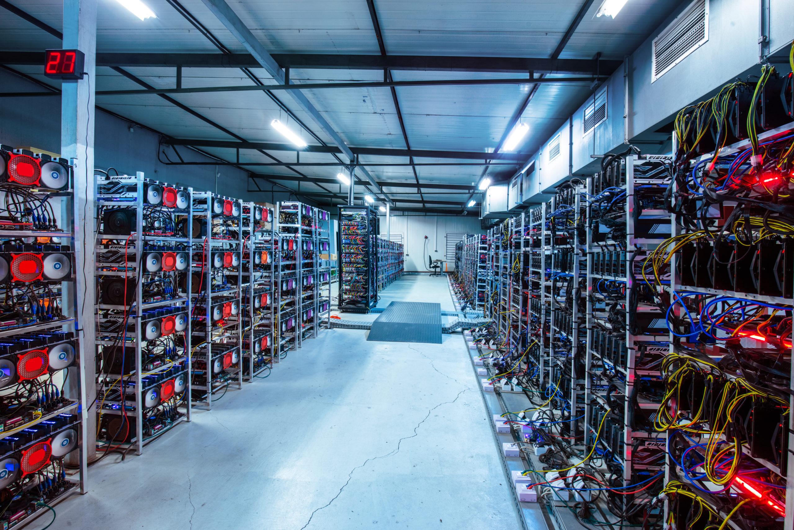 Inside of a bitcoin mining farm with many connected miners, wires, and computers